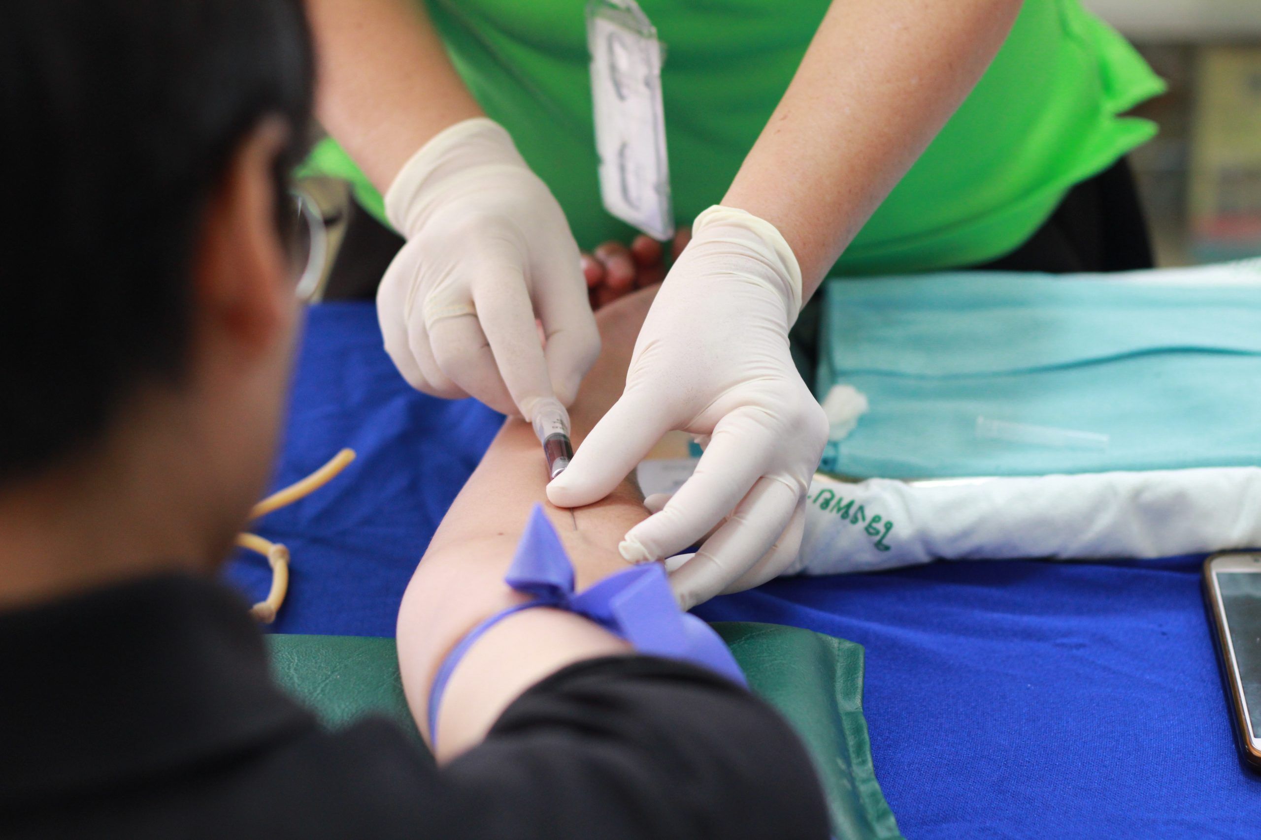 Medical Technician inserting a syringe into a patients arm